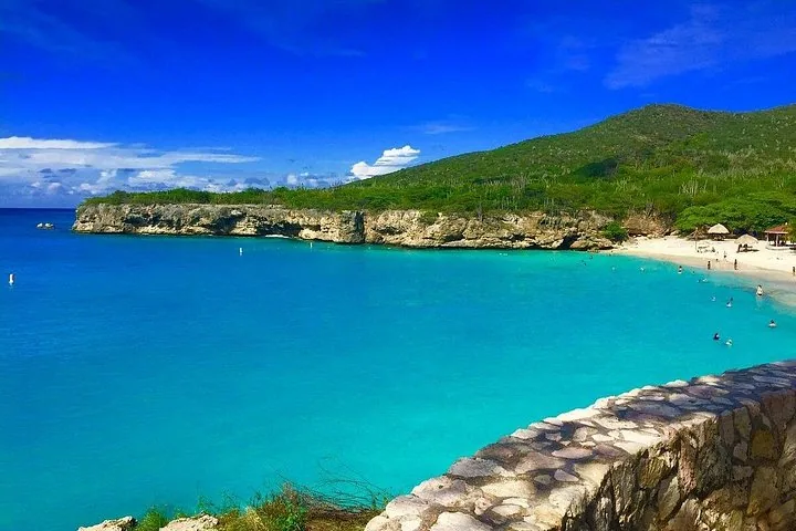 Hermosa bahía de agua turquesa con acantilados rocosos y una playa de arena.
